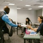 Czy oceny naprawdę motywują? Co mówi psychologia edukacji Nauczyciel rozmawia ze studentami na zajęciach, zachęcając do aktywności