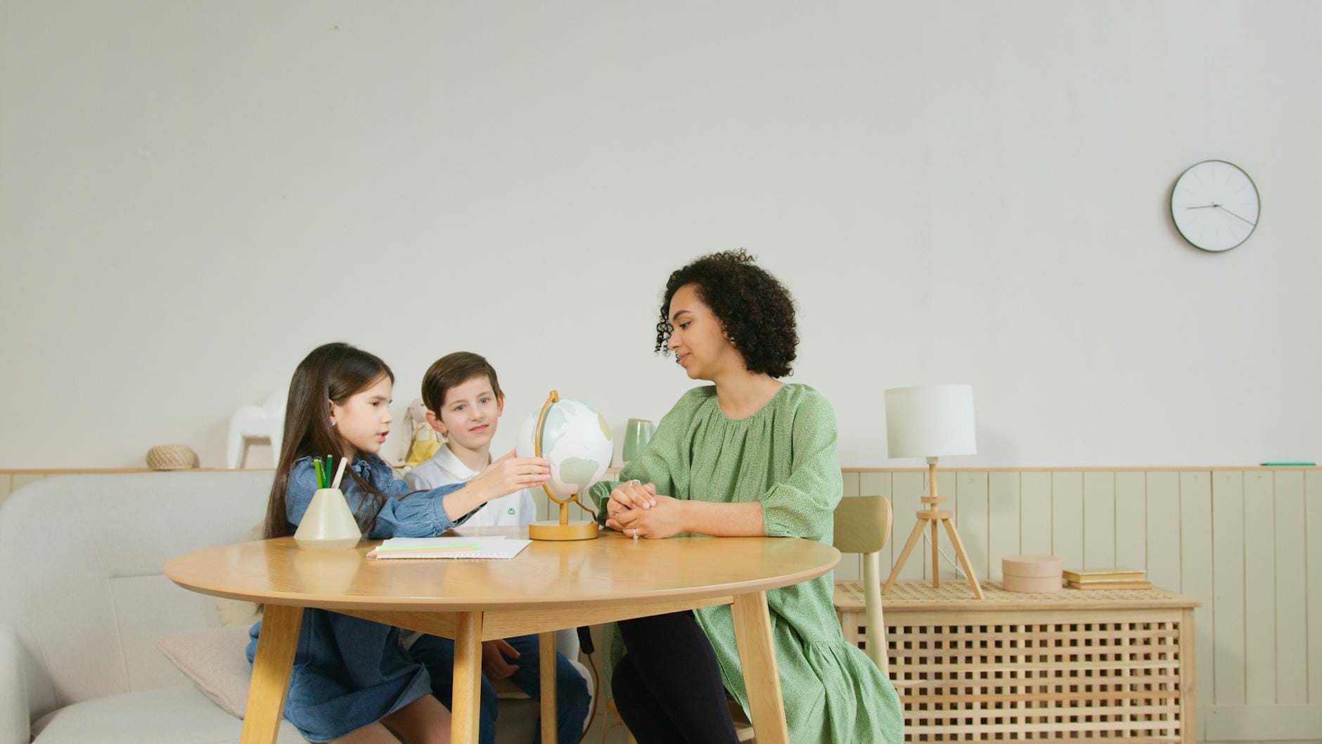 Nauczycielka i dzieci oglądają globus podczas lekcji geografii