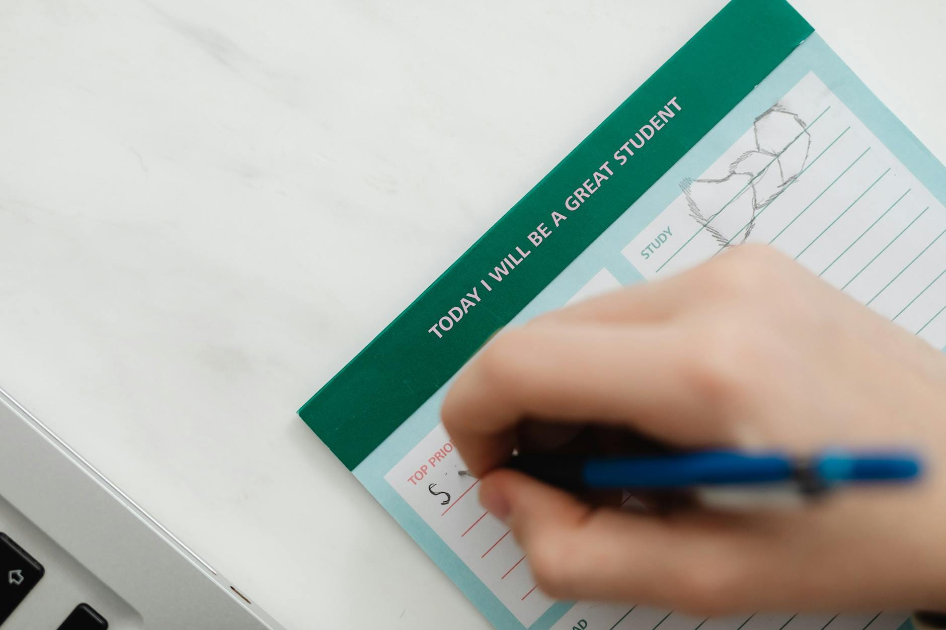 Jak przygotować się do egzaminu bez zarywania nocy i spadku formy? Dłoń pisząca niebieskim długopisem motywacyjną notatkę przed egzaminem