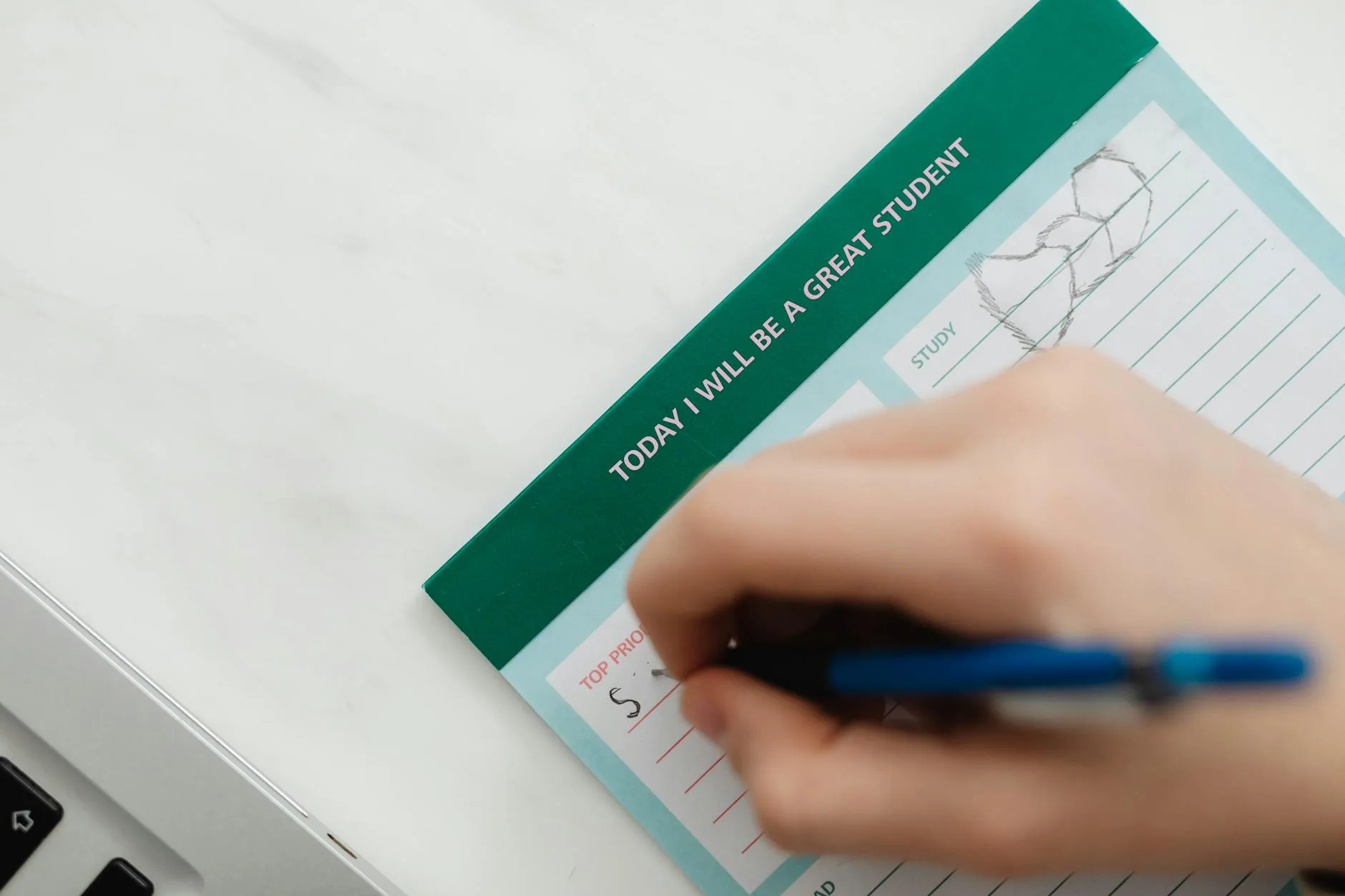 Jak przygotować się do egzaminu bez zarywania nocy i spadku formy? Dłoń pisząca niebieskim długopisem motywacyjną notatkę przed egzaminem