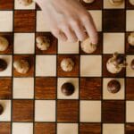 Dłoń przesuwająca pionek szachowy na szachownicy z góry