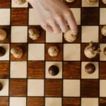 Dłoń przesuwająca pionek szachowy na szachownicy z góry