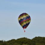 Kolorowy balon na gorące powietrze nad zielonym lasem w słoneczny dzień
