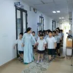 Przyszłość edukacji: czy nauczyciel stanie się trenerem, a nie wykładowcą? Nauczyciel prowadzi uczniów w mundurkach korytarzem szkolnym