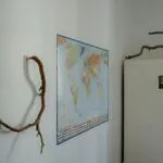 Historia z lodówki: jak wynaleziono sztuczne chłodzenie żywności Stara lodówka w artystycznym wnętrzu z gałęziami i mapą świata