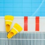 Żółte płetwy pływackie leżące przy brzegu czystego basenu
