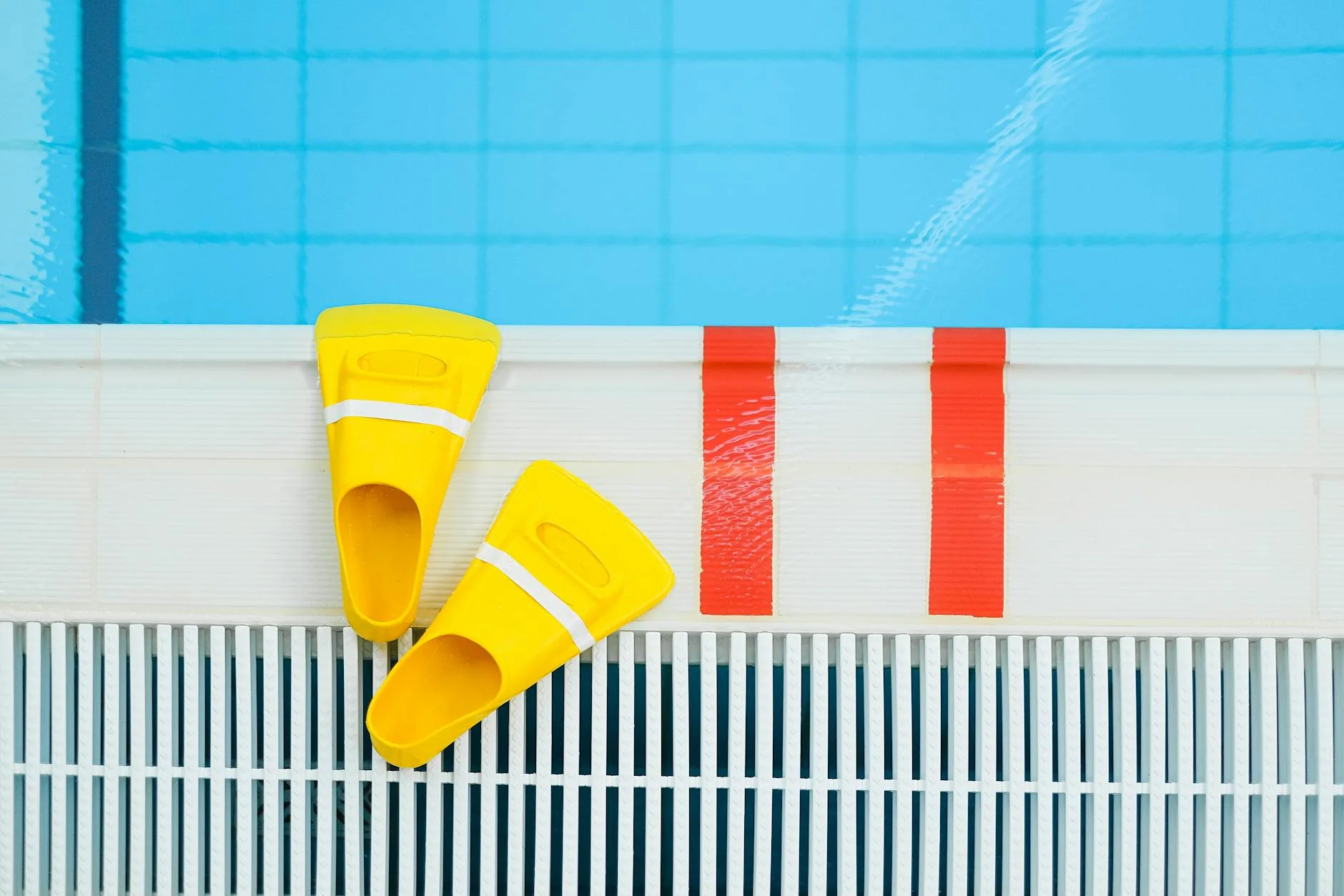 Żółte płetwy pływackie leżące przy brzegu czystego basenu