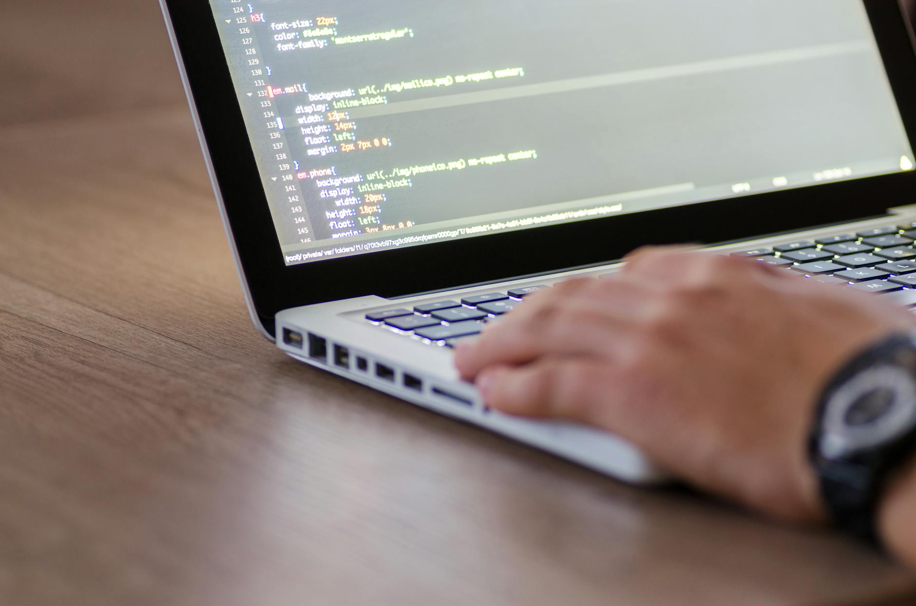 Osoba programująca na laptopie z kodem HTML na ekranie