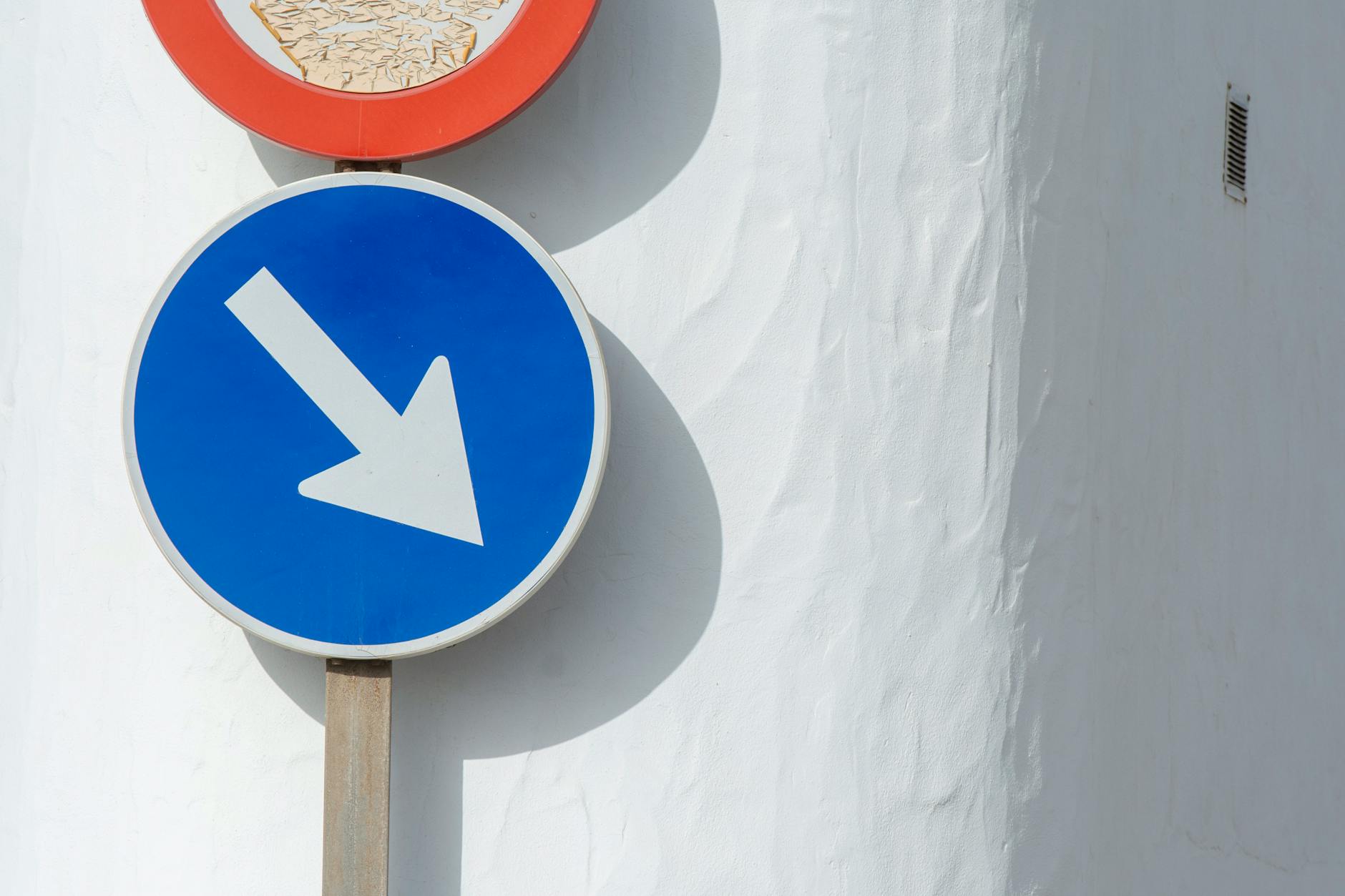 Niebieska strzałka w dół na białej ścianie symbolizująca kierunek czasu