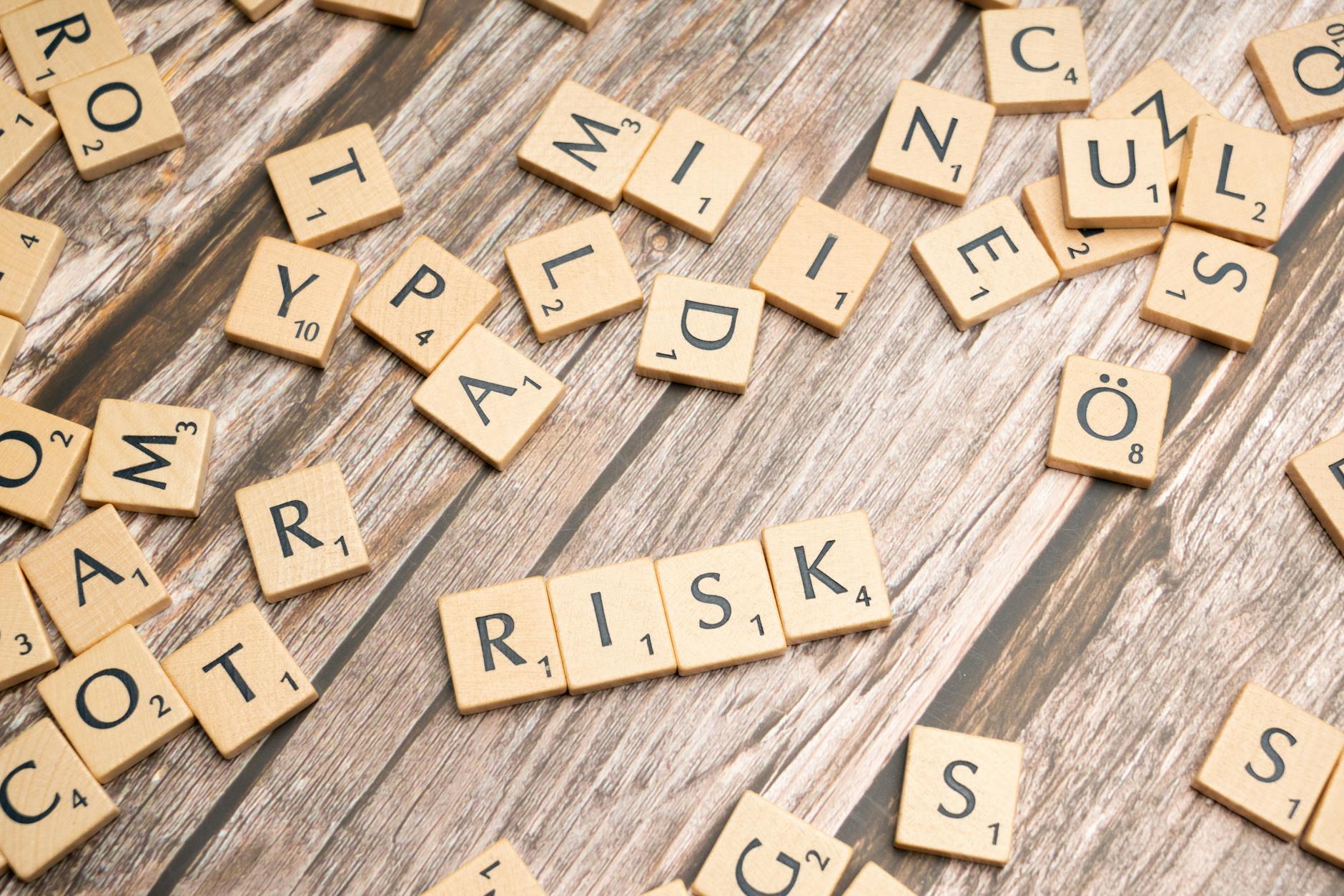 Drewniane klocki Scrabble układające się w słowo risk na stole