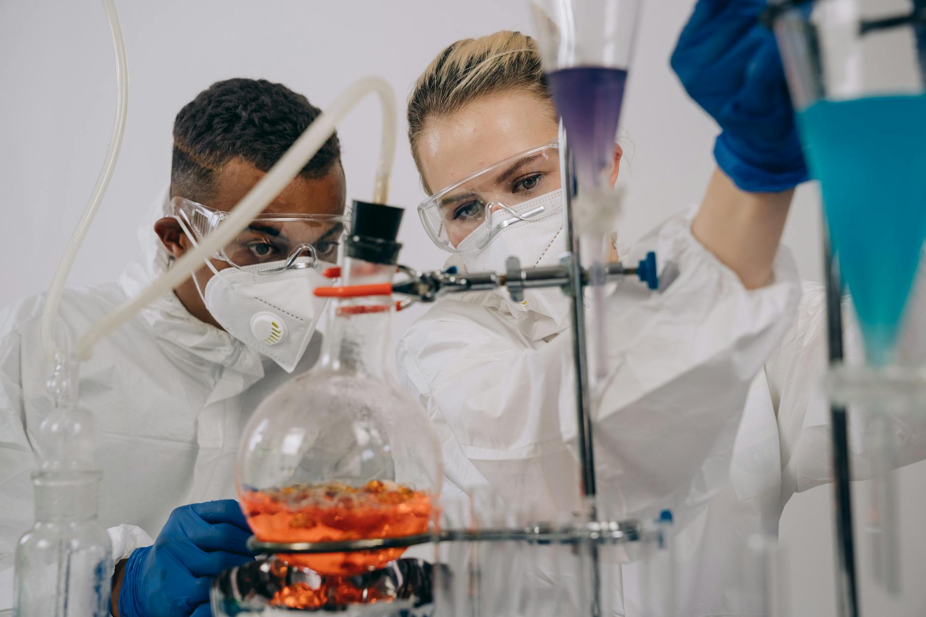Dwóch naukowców w kombinezonach ochronnych pracuje przy eksperymentach chemiczny