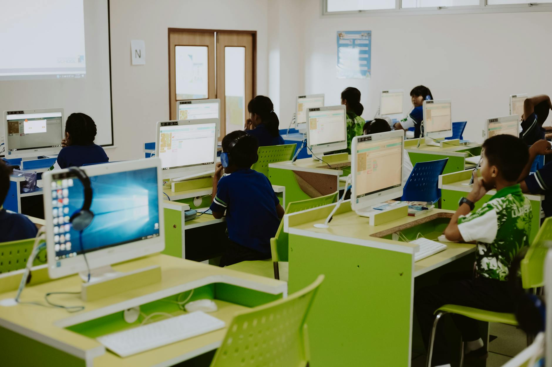 Dzieci uczące się przy komputerach w nowoczesnej szkolnej pracowni