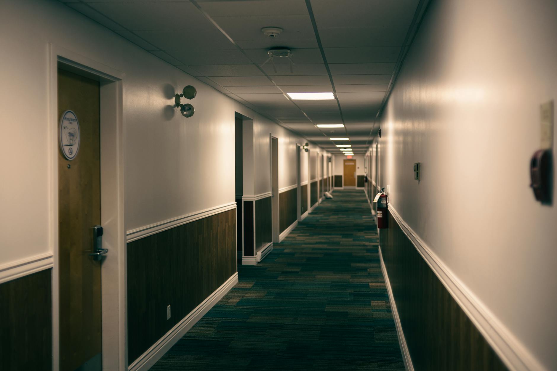 Pusty, cichy korytarz hotelowy z rzędem drewnianych drzwi