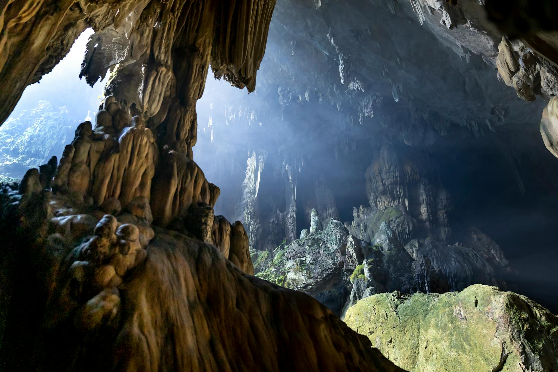 Skały wapienne i stalagmity w jasnej jaskini, światło wpada z góry