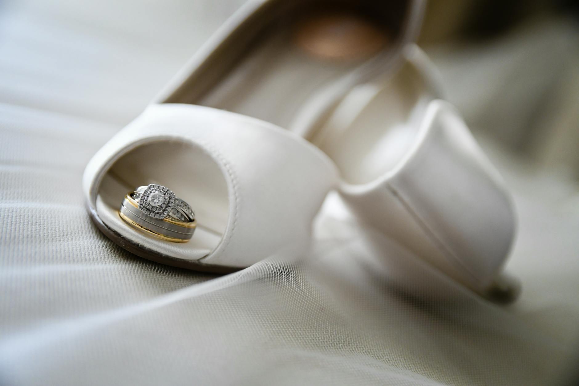 Zbliżenie na ślubne buty panny młodej z diamentowymi obrączkami