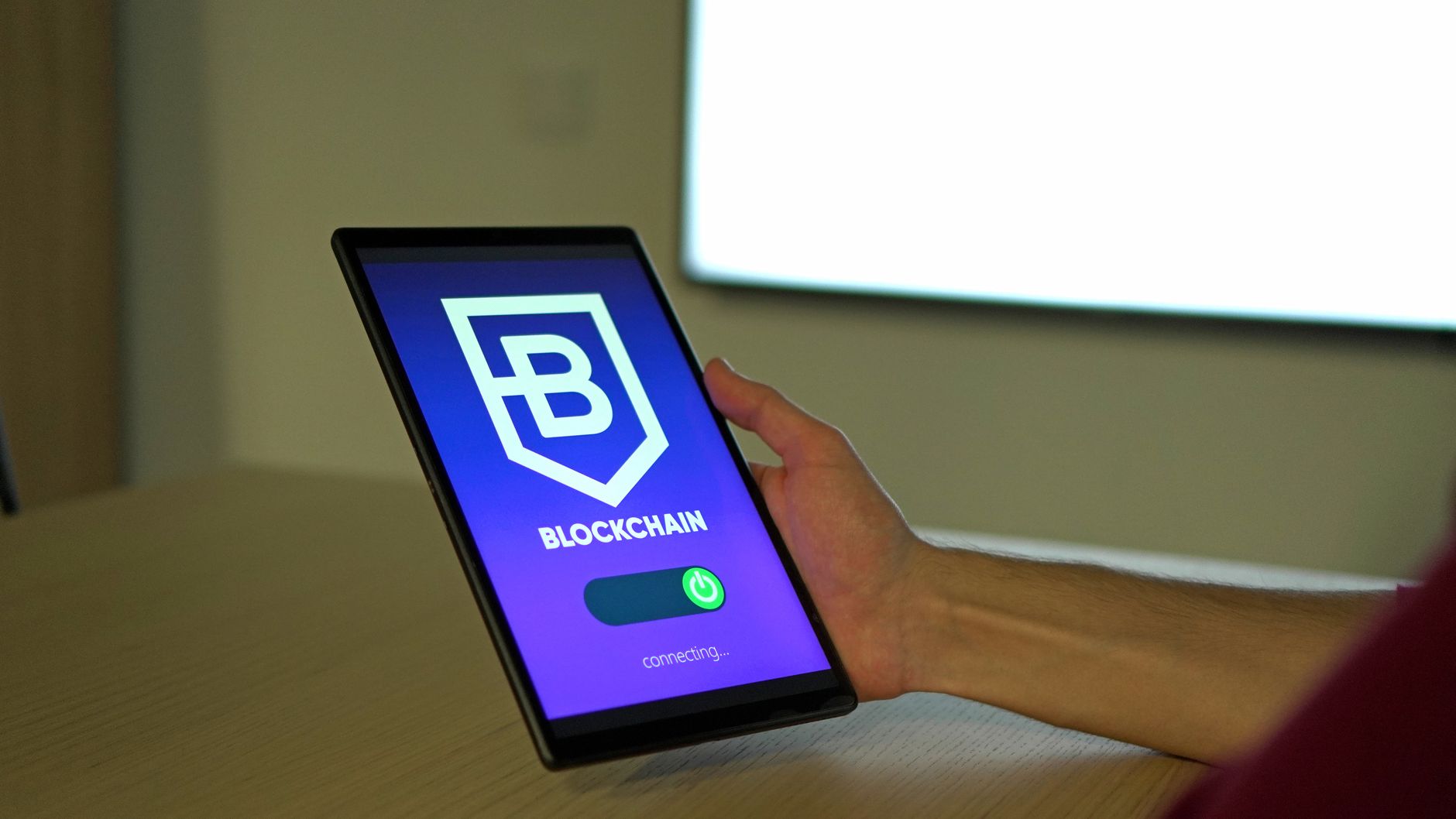 Dłoń trzymająca tablet z logo blockchain, symbol nowoczesnych technologii
